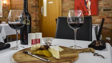Una mesa dispuesta con copas de vino, una botella de Shiraz Black, queso y una tabla de madera con un cuchillo.