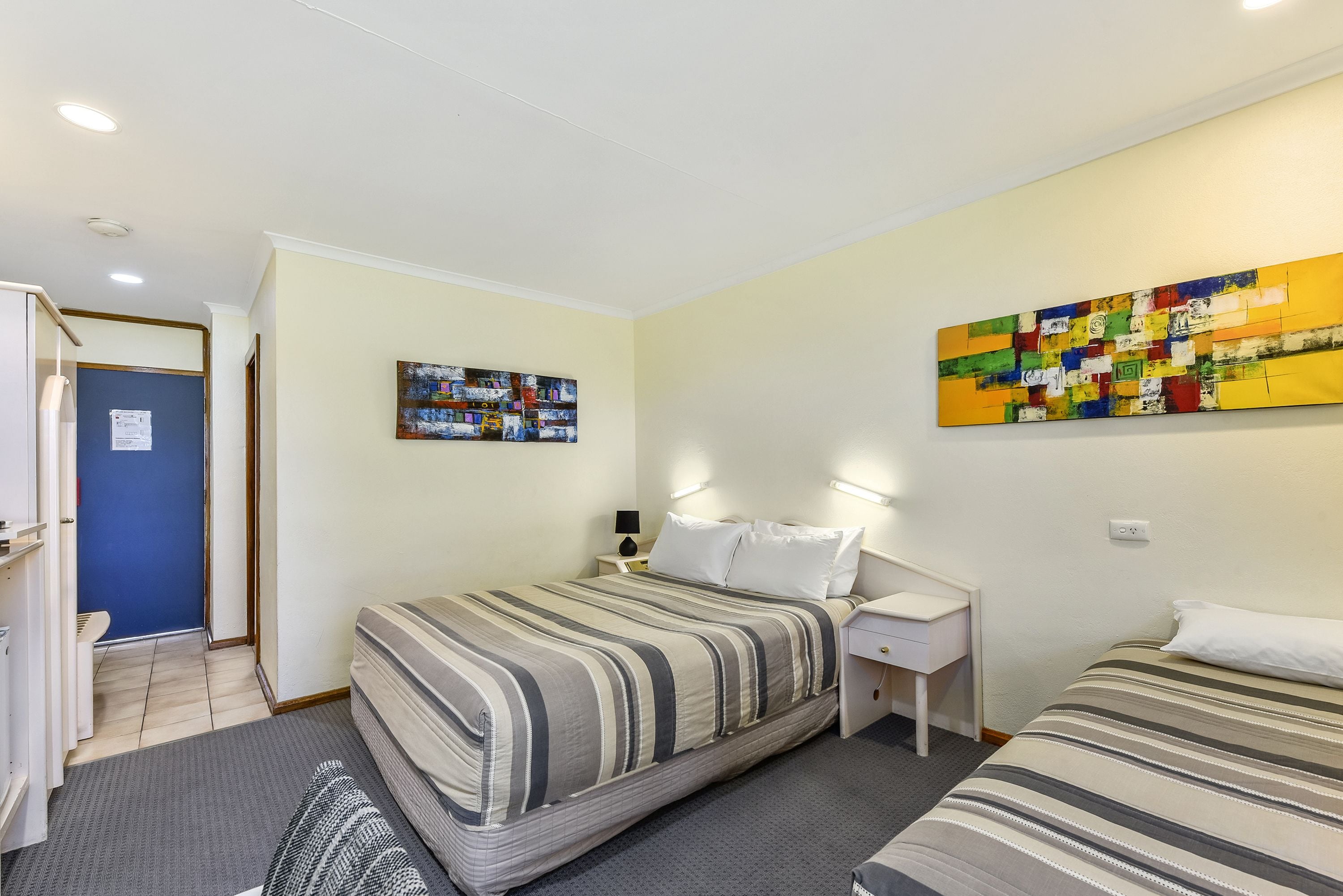 Une chambre d’hôtel avec un lit, une table de chevet et une œuvre d’art murale.