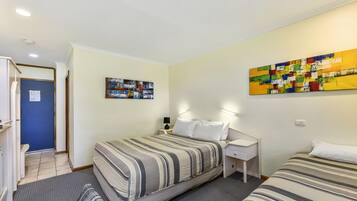 Une chambre d’hôtel avec un lit, une table de chevet et une œuvre d’art murale.