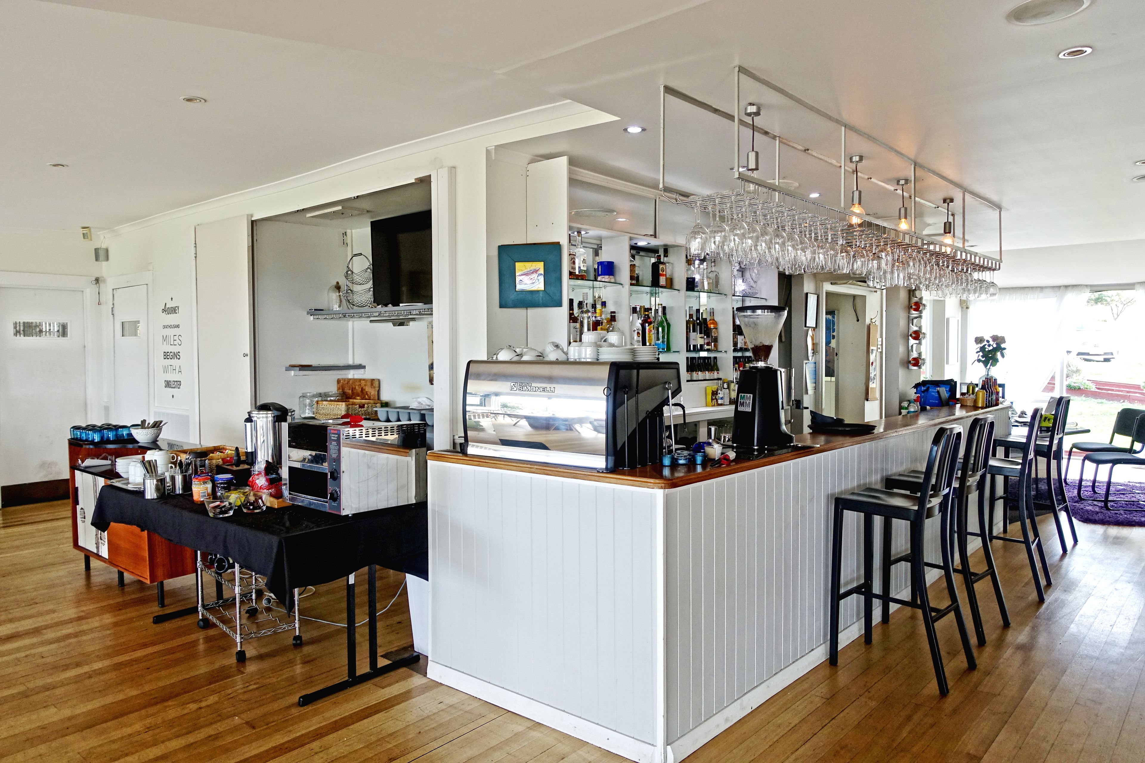 A modern kitchen with a central island, bar area with stools, and a dining area with chairs.