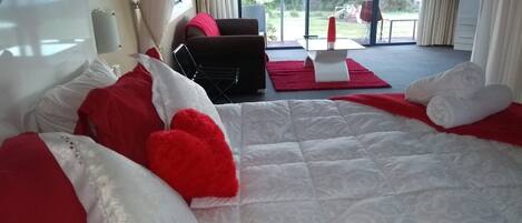 Un dormitorio con una cama grande, un escritorio y vistas al exterior.