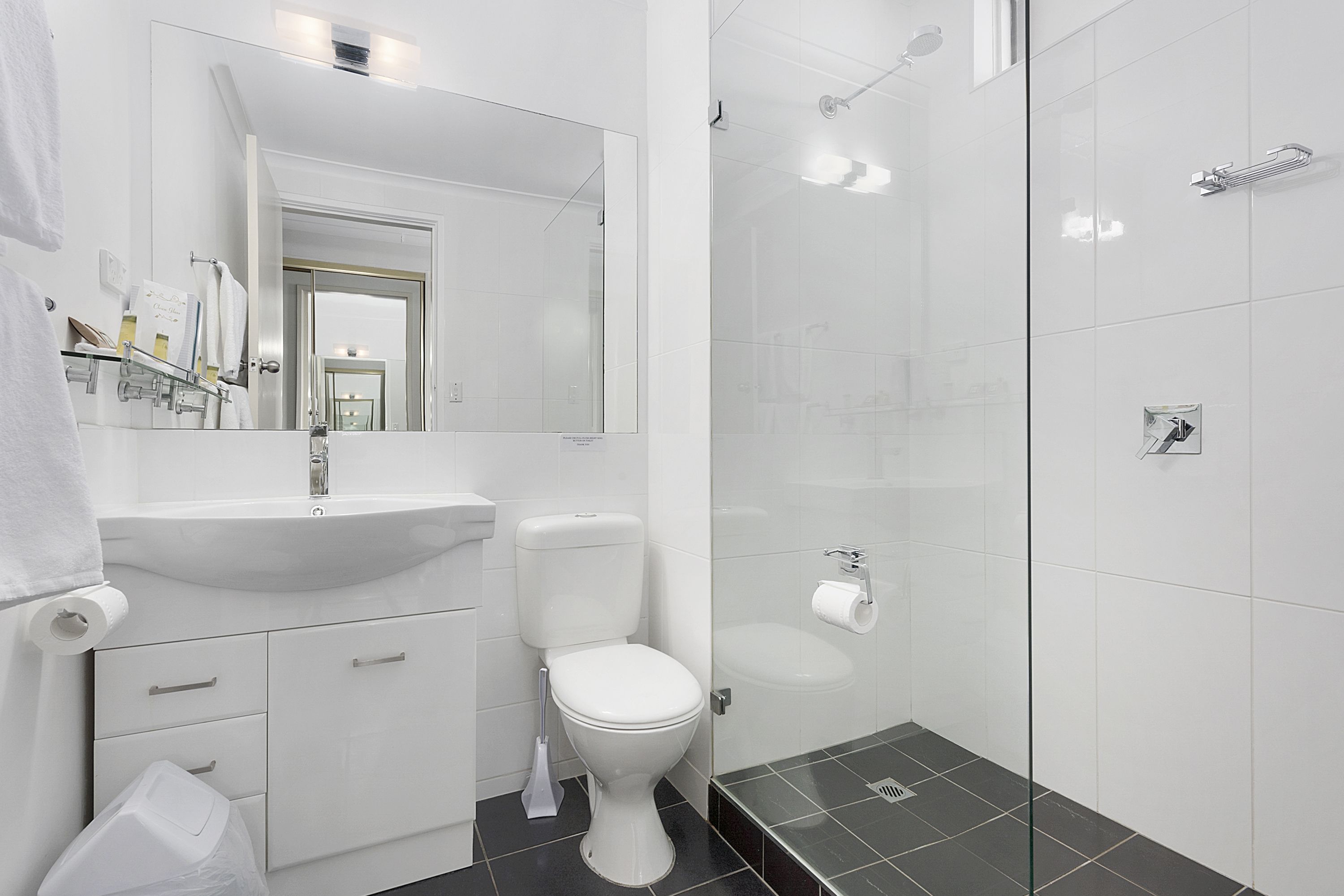 A modern bathroom with a white sink, toilet, and glass shower enclosure.