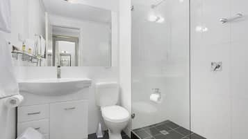 Een moderne badkamer met een witte wastafel, toilet en een douchecabine met glazen wanden.