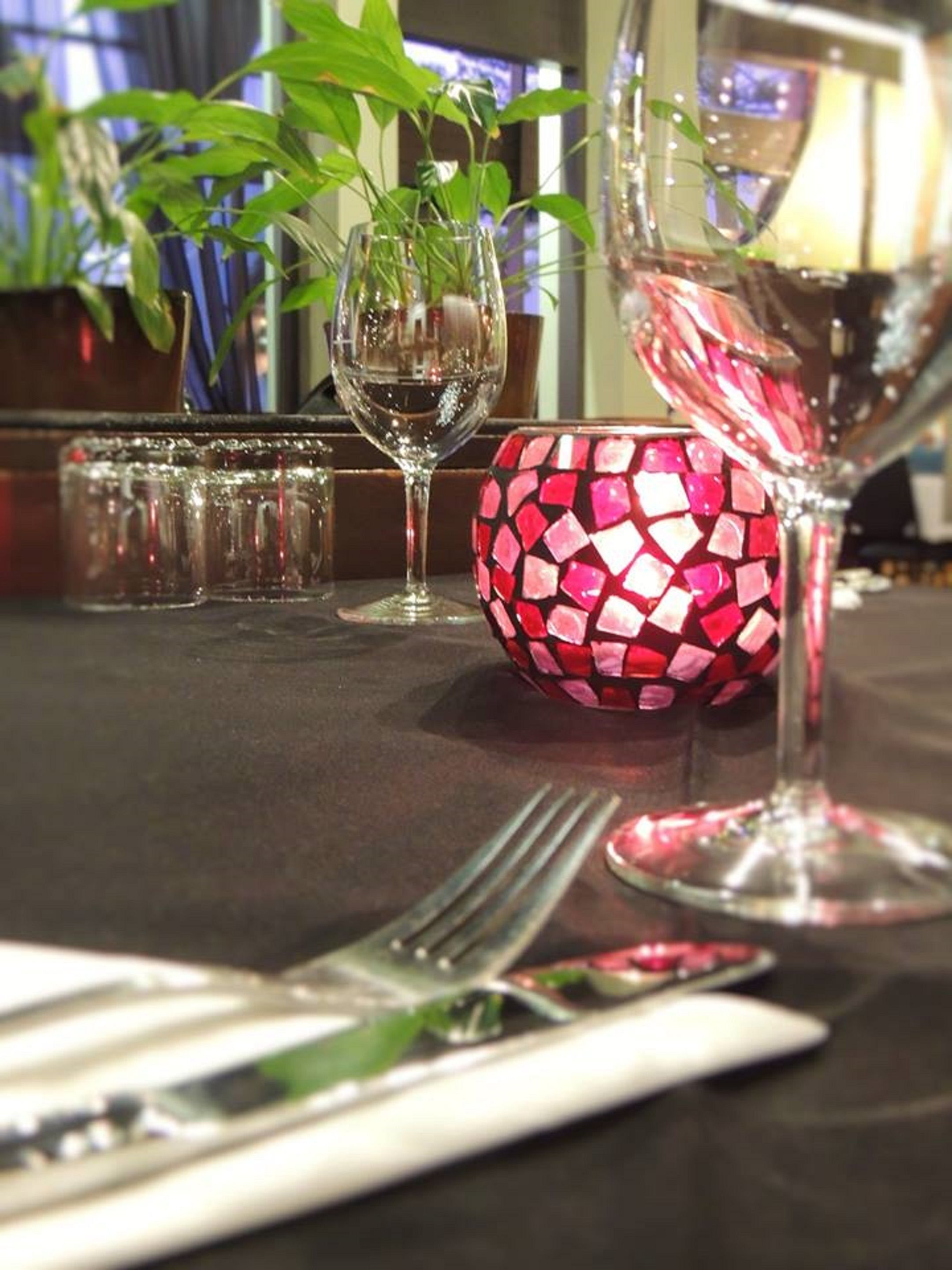 Una mesa de comedor con una copa de vino, un cuenco de mosaico y un tenedor.