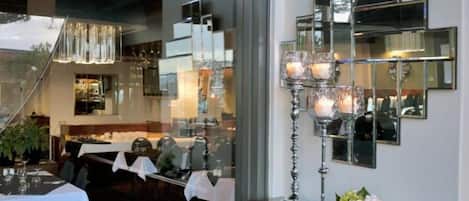 Un interior de restaurante con una larga mesa de comedor, sillas y una araña.