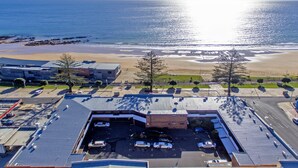 Vista aérea de un estacionamiento con una playa y el océano al fondo.