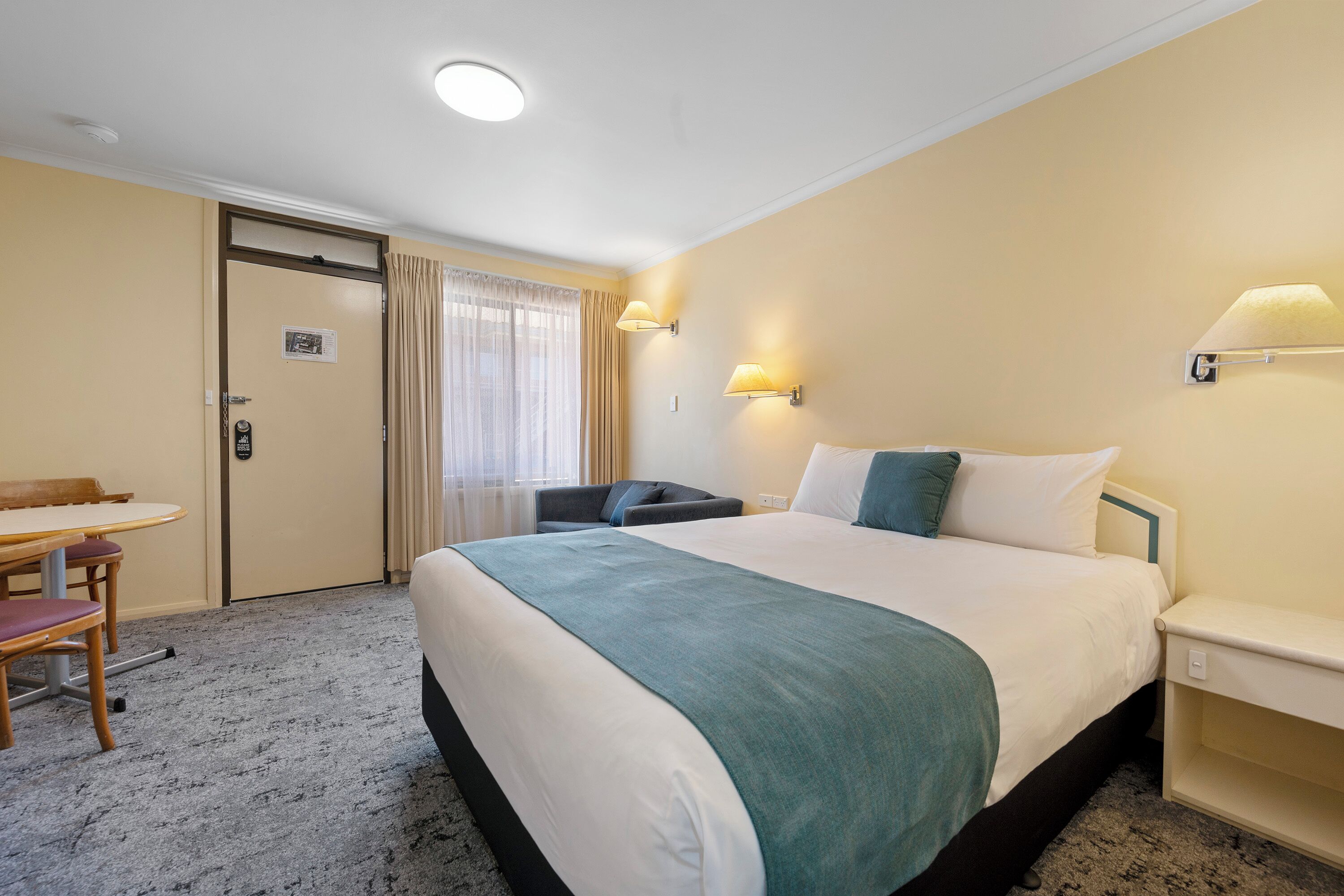 A hotel room with a bed, a desk, and a chair.