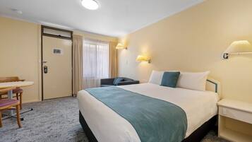 A hotel room with a bed, a desk, and a chair.
