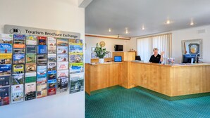 A reception area with a wooden desk, a computer, and a wall displaying various tourism brochures. - Comfort Inn Devonport (Devonport)