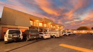 A parking lot with several vehicles, including a police SUV and a fire truck, in front of a building with multiple floors and balconies. - Comfort Inn Devonport (Devonport)
