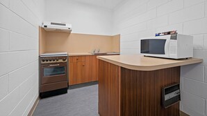 A compact kitchen with a built-in oven, microwave, and wooden cabinets. - Comfort Inn Devonport (Devonport)