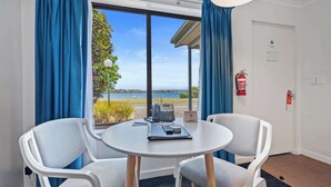 A room with a round table, two chairs, a phone, a notepad, and a pen. A fire extinguisher is mounted on the wall. - Comfort Inn The Pier (George Town)