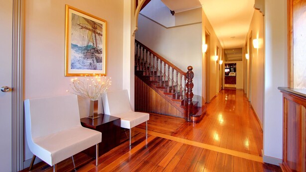 A hallway with wooden flooring, a staircase, and a framed painting on the wall. - Comfort Inn The Pier (George Town)
