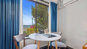 A room with a round table, two chairs, a telephone, and a window with curtains.