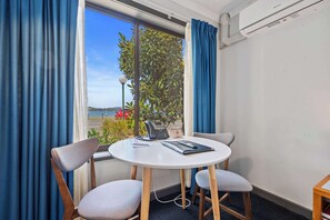 A room with a round table, two chairs, a telephone, and a window with curtains.