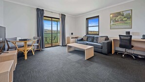 A modern living room with a sofa, coffee table, and a dining area with a table and chairs. There is a balcony with a view of the landscape. - Comfort Inn The Pier (George Town)