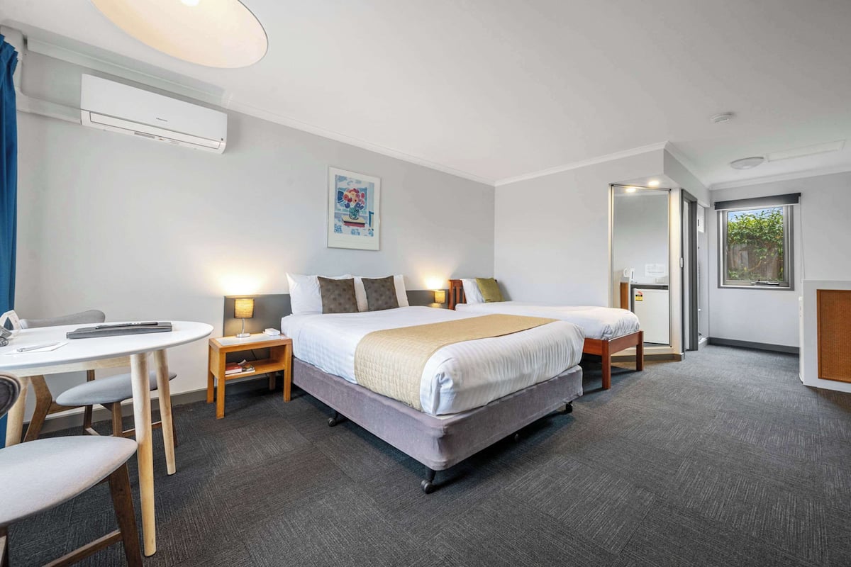 A hotel room with a bed, bedside tables, a desk, and a chair.