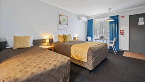 A hotel room with two beds, a desk, a chair, a table, and a window with curtains.