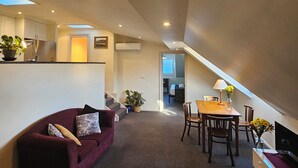 A compact living space with a dining area, a sofa, and a staircase leading to another room. - The Lodge on Elizabeth (North Hobart)