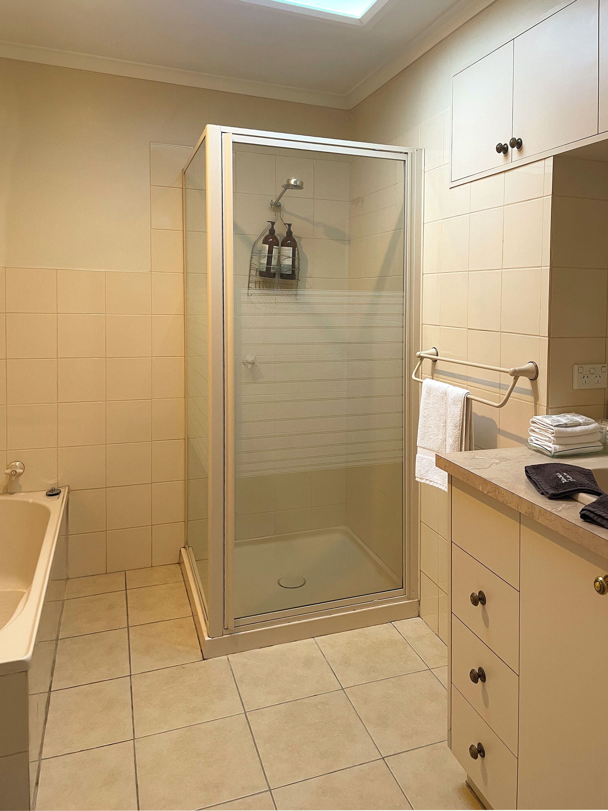 A bathroom with a glass-enclosed shower, a bathtub, and a vanity with a mirror.
