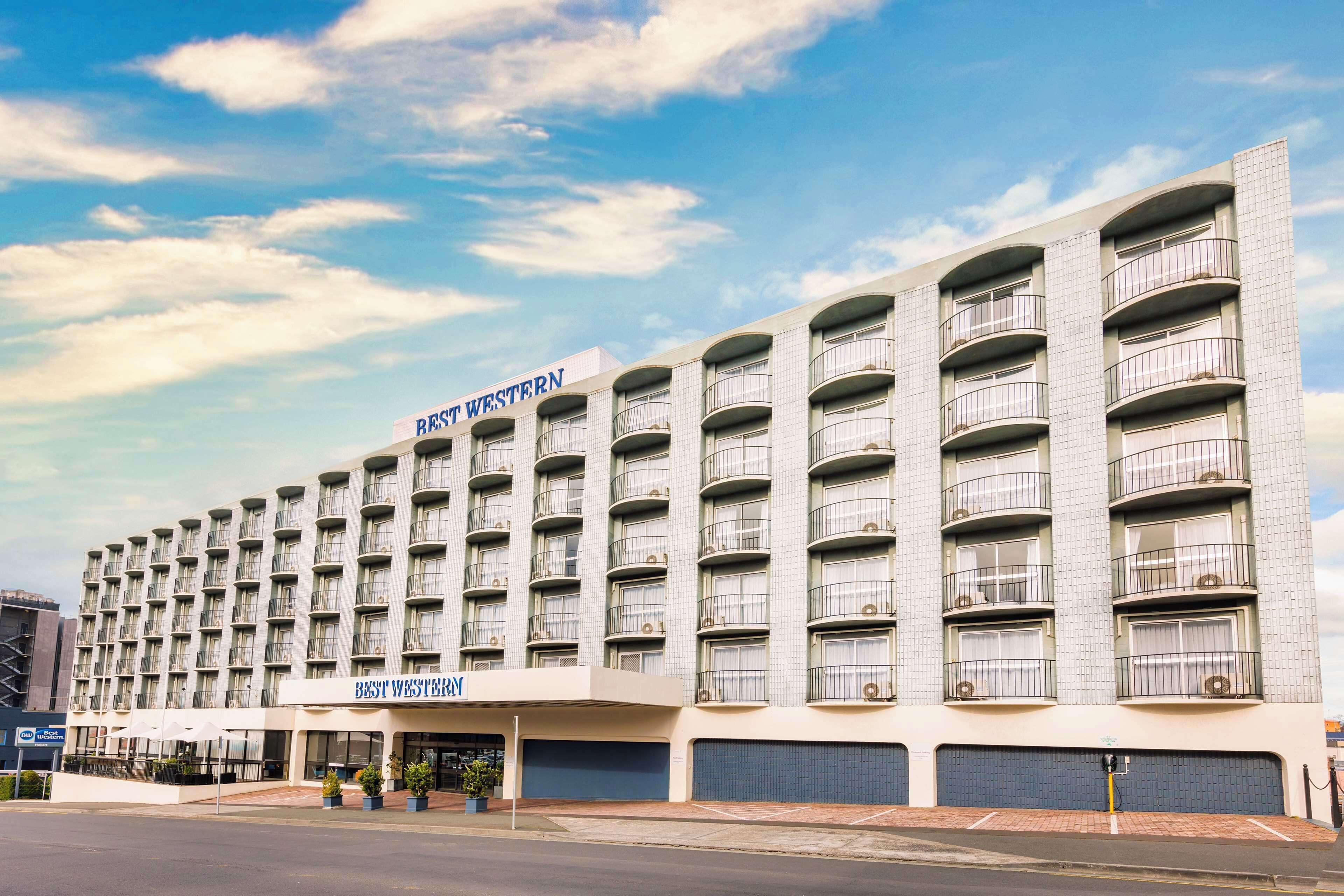 A multi-story hotel with a modern design, featuring balconies on each floor and a prominent signage for "Best Western".
