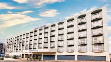 A multi-story hotel with a modern design, featuring balconies on each floor and a prominent signage for "Best Western".