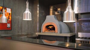 A modern kitchen with a built-in wood-fired oven, stainless steel appliances, and pendant lighting. - Best Western Hobart (Hobart)