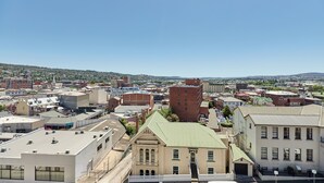 A cityscape with various buildings, including a prominent red brick building and a beige building with a green roof. - Balmoral On York (Launceston)