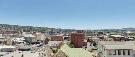 A cityscape with various buildings, including a prominent red brick building and a beige building with a green roof.