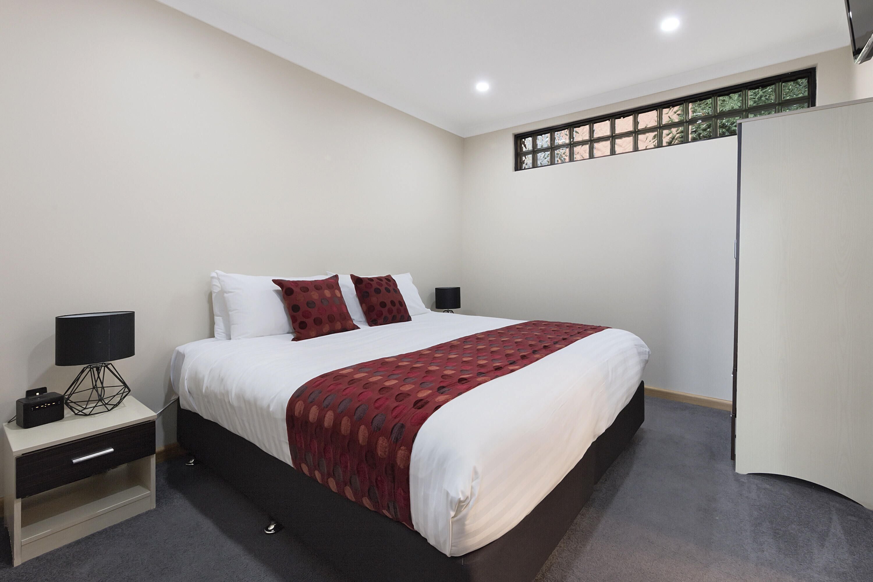 Un dormitorio ordenado con cama, mesitas de noche y mesilla.