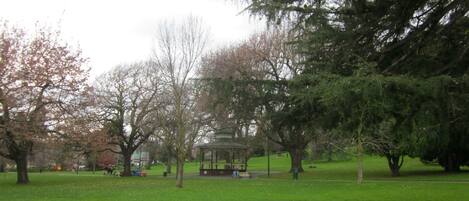 A park with a gazebo, green grass, and trees.