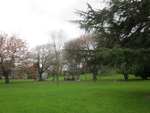 A park with a gazebo, green grass, and trees.