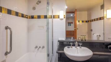 A modern bathroom with a glass-enclosed shower, a white bathtub, and a black countertop with a sink.