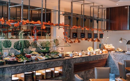 A buffet area with various food items, a seating area with chairs, and a decorative plant display.