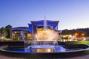 A modern building with a central fountain, surrounded by a landscaped area.