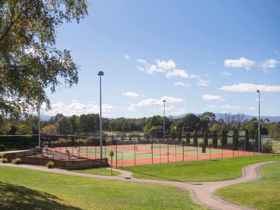 A baseball field with a dirt infield, a green outfield, and a surrounding fence.