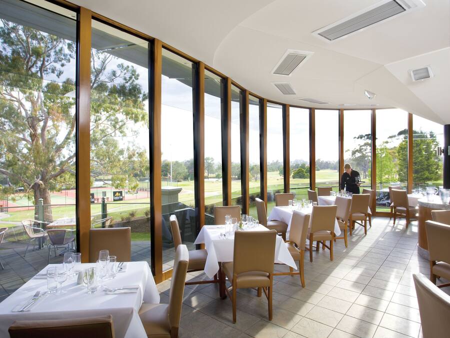 A restaurant with large windows, tables set for dining, and a view of the outdoors.