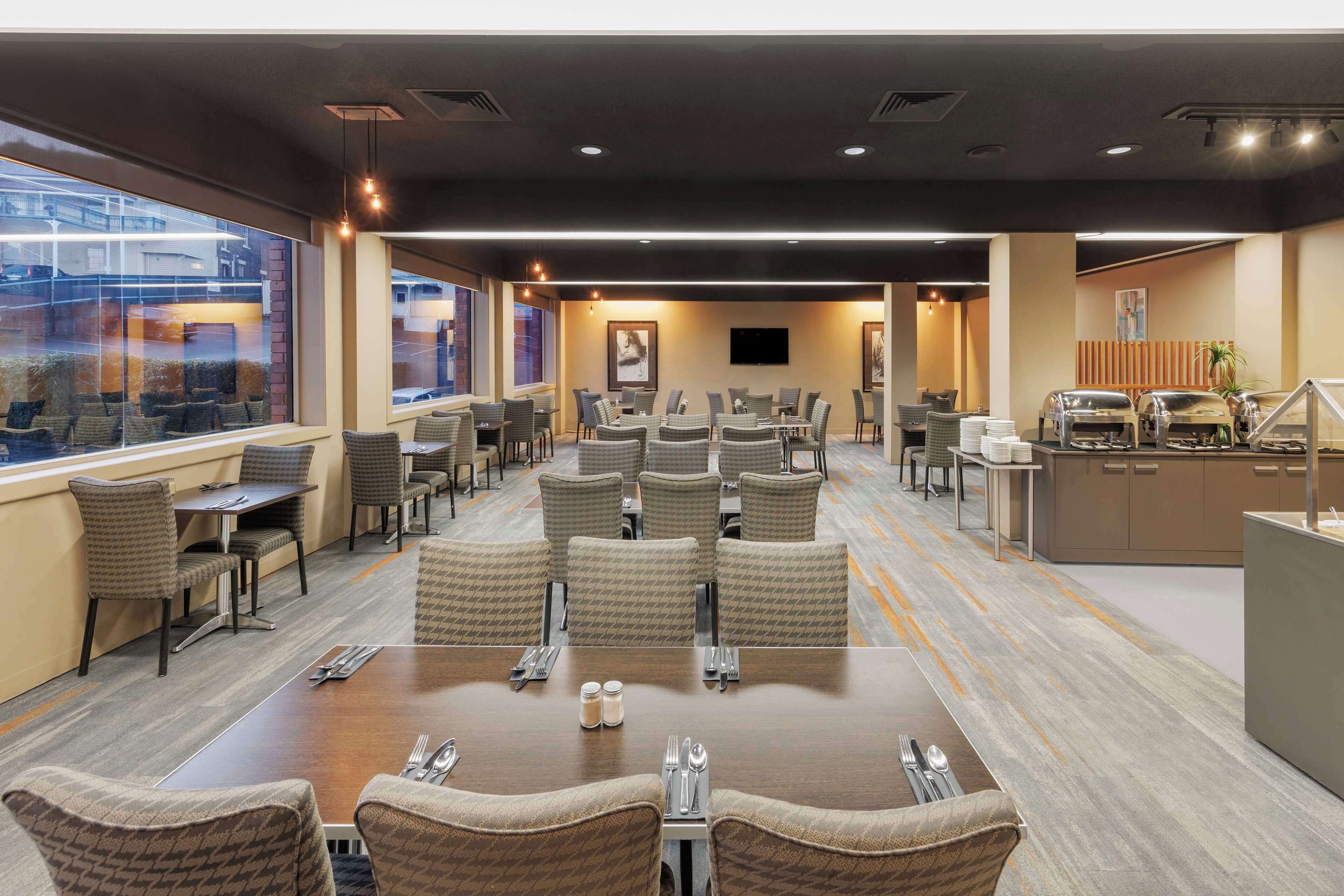 A conference room with a large table, multiple chairs, a buffet area, and a television screen.