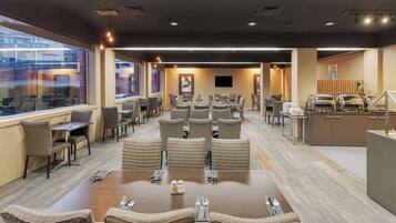A conference room with a large table, multiple chairs, a buffet area, and a television screen.