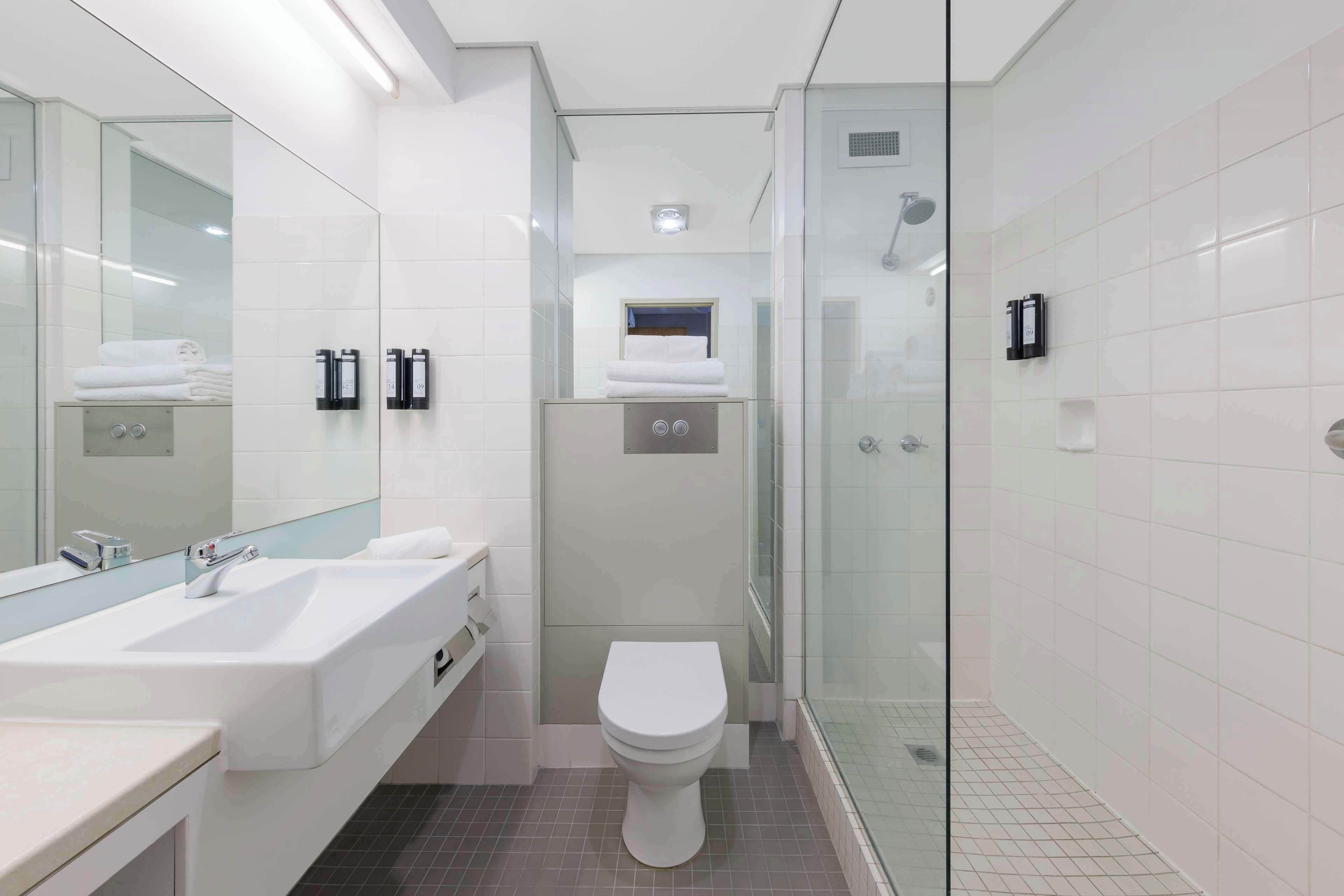 A modern bathroom with a glass-enclosed shower, a white sink, and a toilet.