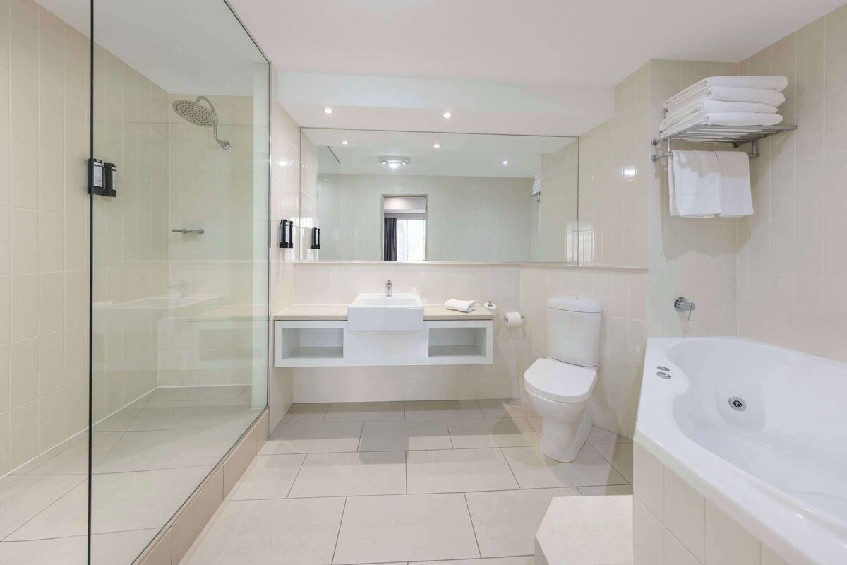 A modern bathroom with a glass-enclosed shower, a white sink, a toilet, and a large bathtub.