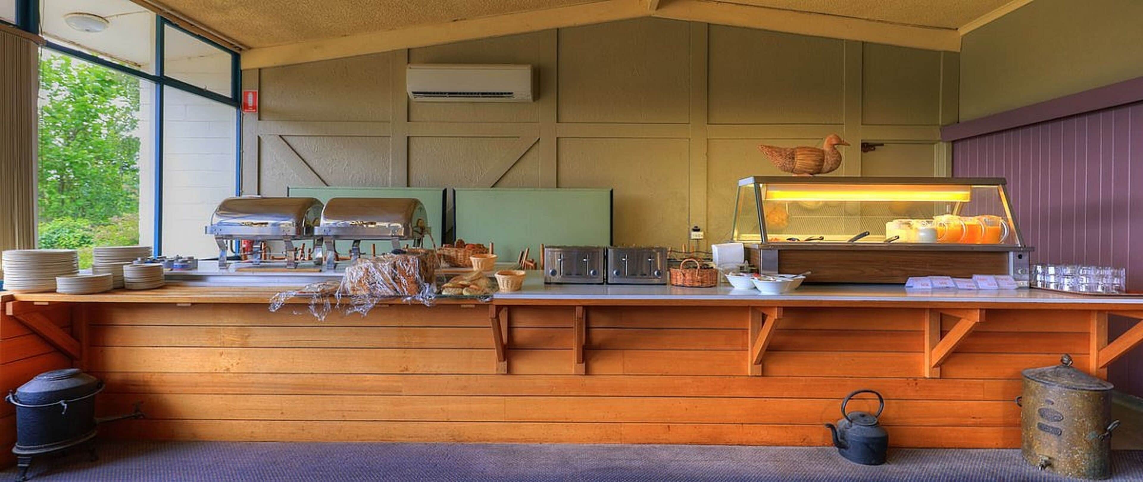 Una encimera de madera rústica con un expositor de vidrio, rodeada de diversos utensilios y objetos de cocina.
