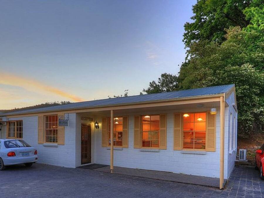A single-story motel with a reception area, a parking lot, and a car parked in front.