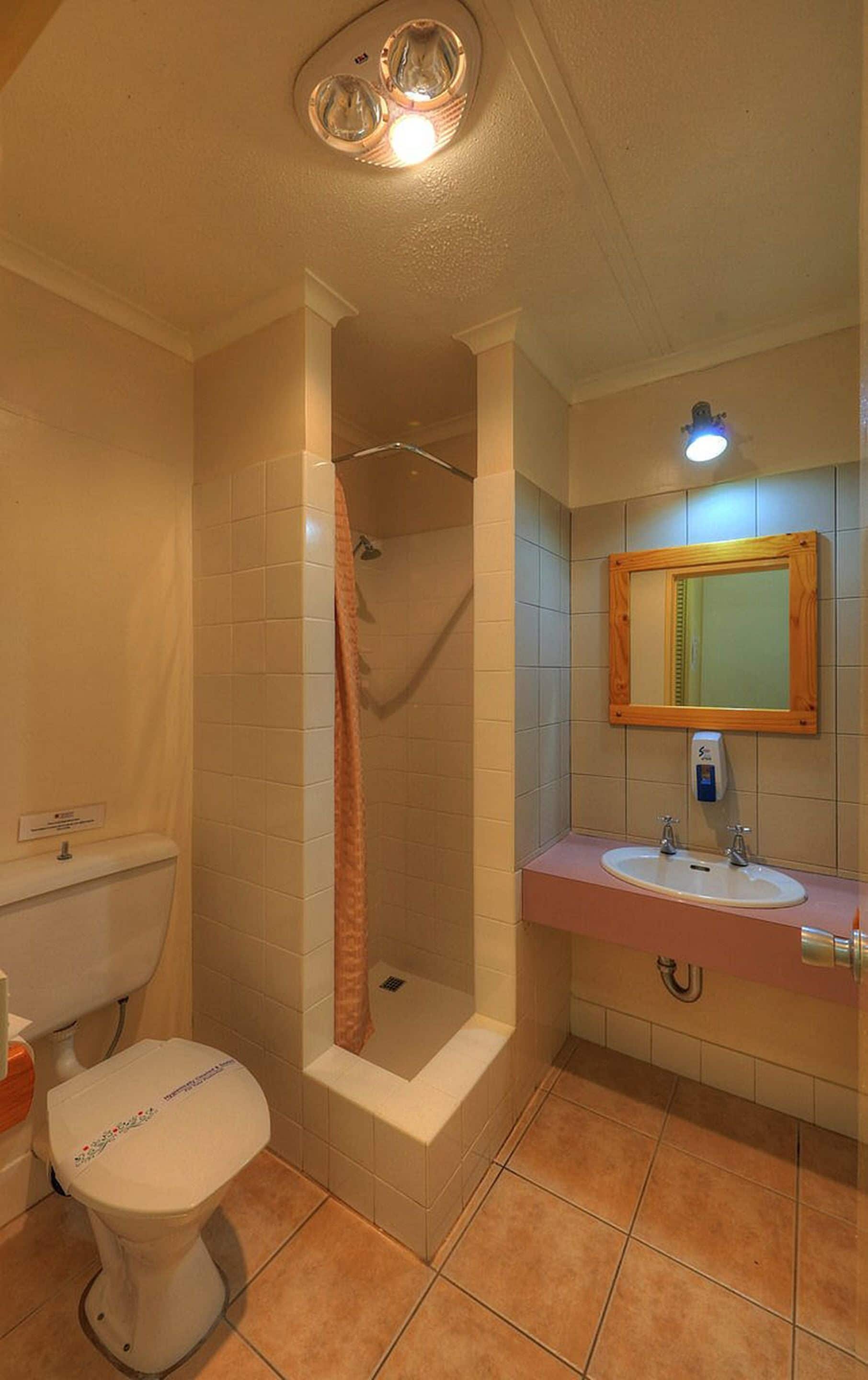 A bathroom with a toilet, shower, and sink.