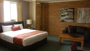 A hotel room with a bed, a coffee table, a sofa, and a brick wall.