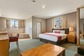 A hotel room with a bed, bedside table, lamp, chair, and a small desk with a chair. - Quality Inn Colonial (Golden Square)