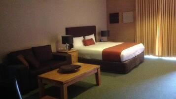 Una habitación de hotel con cama, sofá, una mesita y una lámpara.