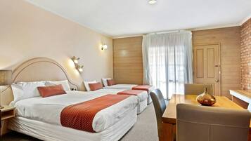 Habitación de hotel con tres camas, una mesa de comedor y una silla.