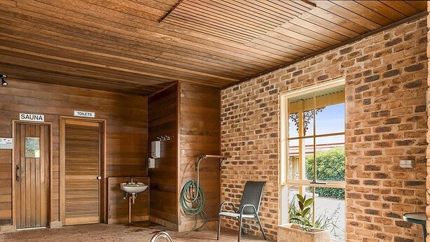 A spa area with a hot tub, wooden walls, a window, and a chair. - Quality Inn Colonial (Golden Square)