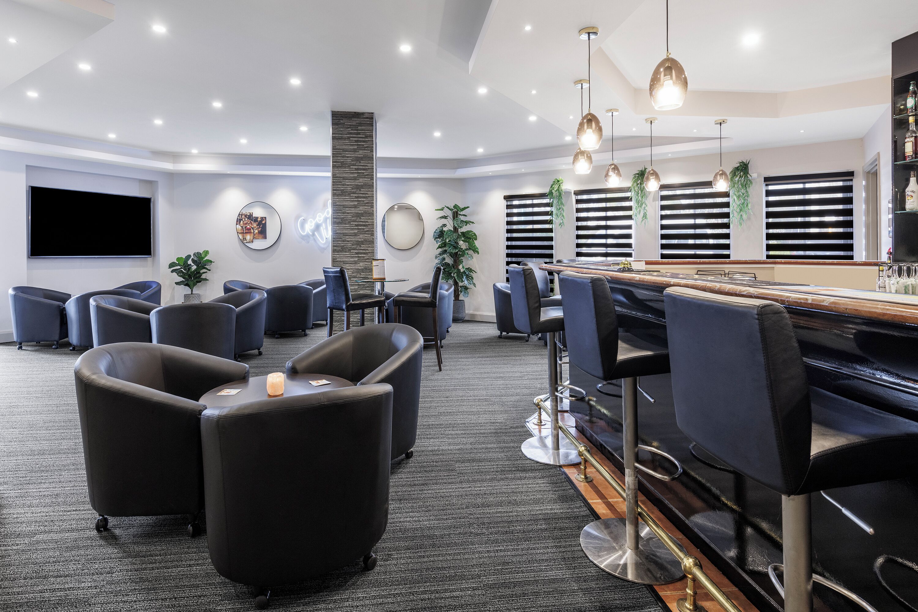 A modern lounge area with seating, a bar, and a flat-screen TV.